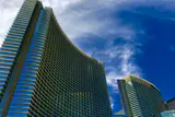 ARIA's curved glass hotel towers rising against a blue sky with wispy clouds