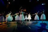 Ballet dancers in white tutus performing on a dark stage under spotlights