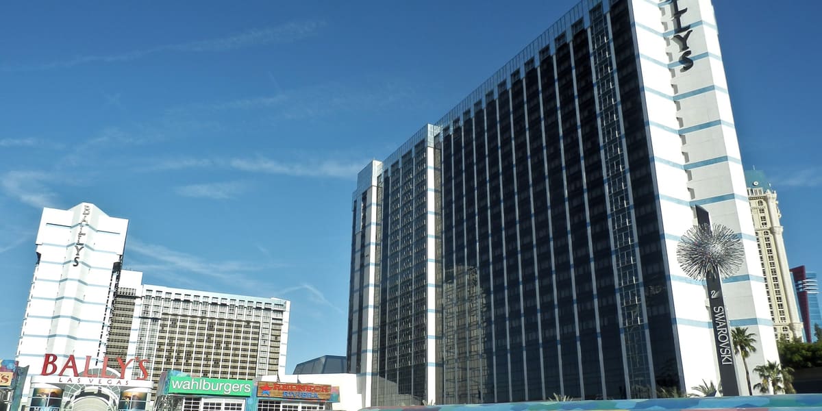 Dark glass hotel tower with Bally's signage and the Grand Bazaar Shops canopy in front