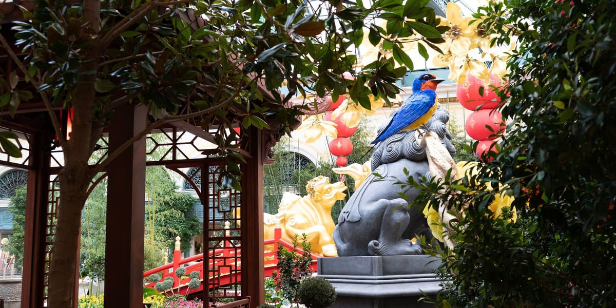 Garden display with trees, flowers, a pavilion and a stone lion sculpture inside the Bellagio Conservatory