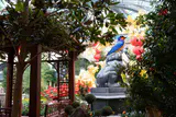 Garden display with trees, flowers, a pavilion and a stone lion sculpture inside the Bellagio Conservatory