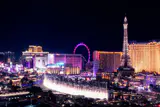 The Bellagio fountains in front of the center Las Vegas Strip at night, with hotel towers and an Eiffel Tower replica