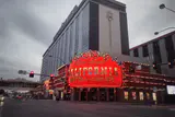 Red neon California Hotel & Casino marquee beneath the hotel tower at a downtown street corner
