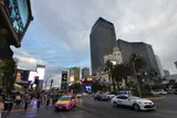 The Cosmopolitan's tall glass towers seen from a busy Las Vegas Boulevard sidewalk under a cloudy sky
