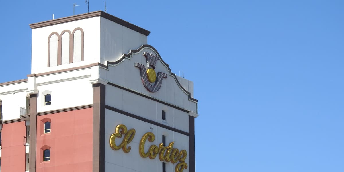 Top of the El Cortez hotel tower with its gold script logo against a blue sky