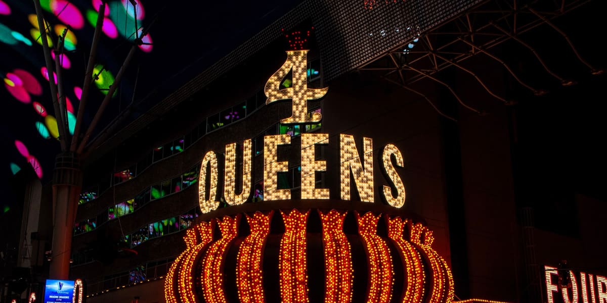 Lit 4 Queens marquee sign with gold bulbs above the casino entrance at night