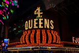 Lit 4 Queens marquee sign with gold bulbs above the casino entrance at night