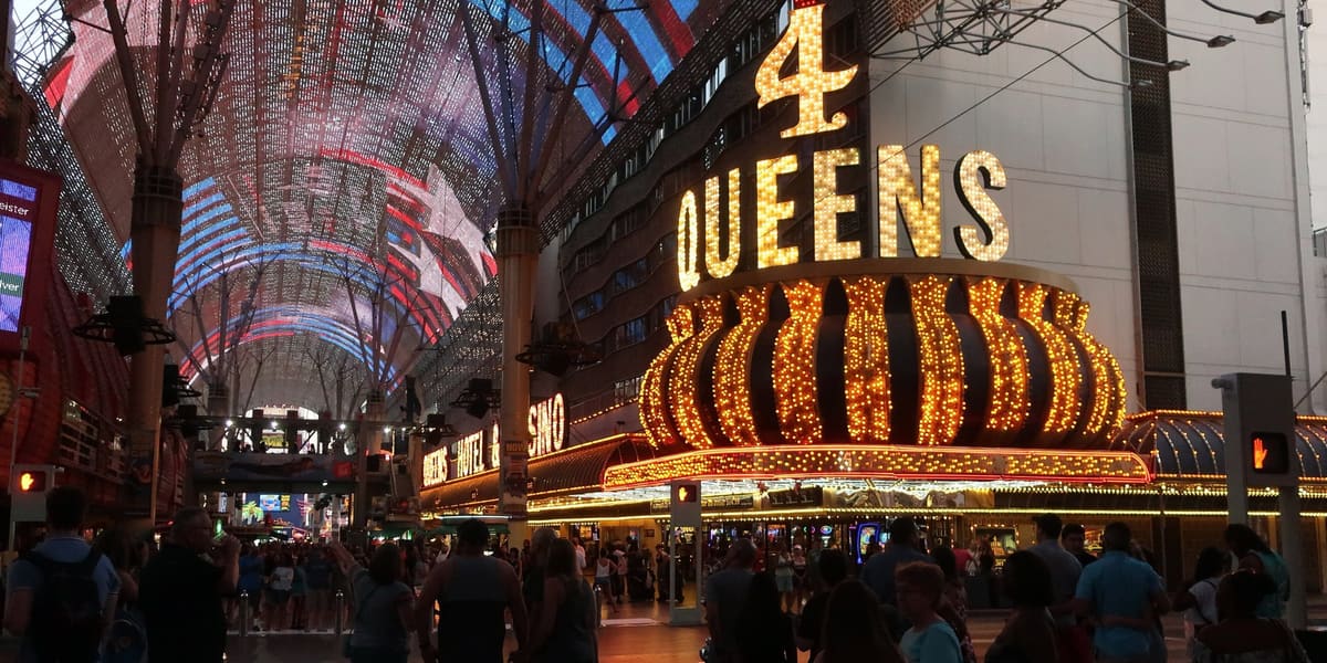 Crowds under the lit Fremont Street Experience canopy beside the Four Queens neon sign at night