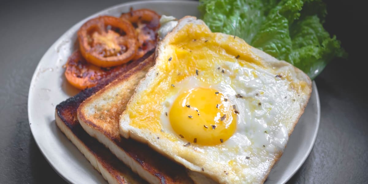 Plate with a fried egg on toast, grilled tomato slices, more toast and fresh lettuce