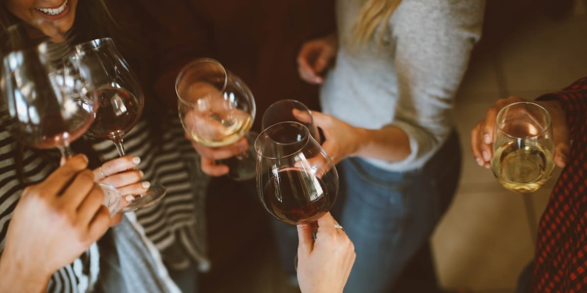 Overhead view of a group of friends clinking wine glasses together in a toast