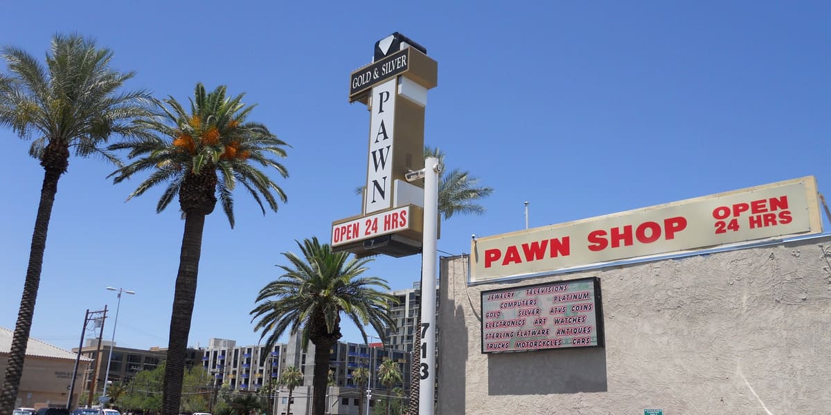 Gold & Silver Pawn shop sign and storefront on Las Vegas Boulevard under a clear blue sky with palm trees