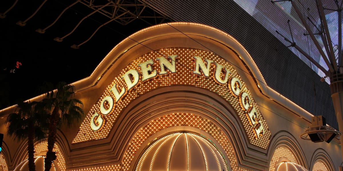 Golden Nugget's illuminated gold arch sign and canopied entrance on Fremont Street at night