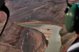 The river and canyon walls seen through a helicopter window, with a passenger headset in the foreground