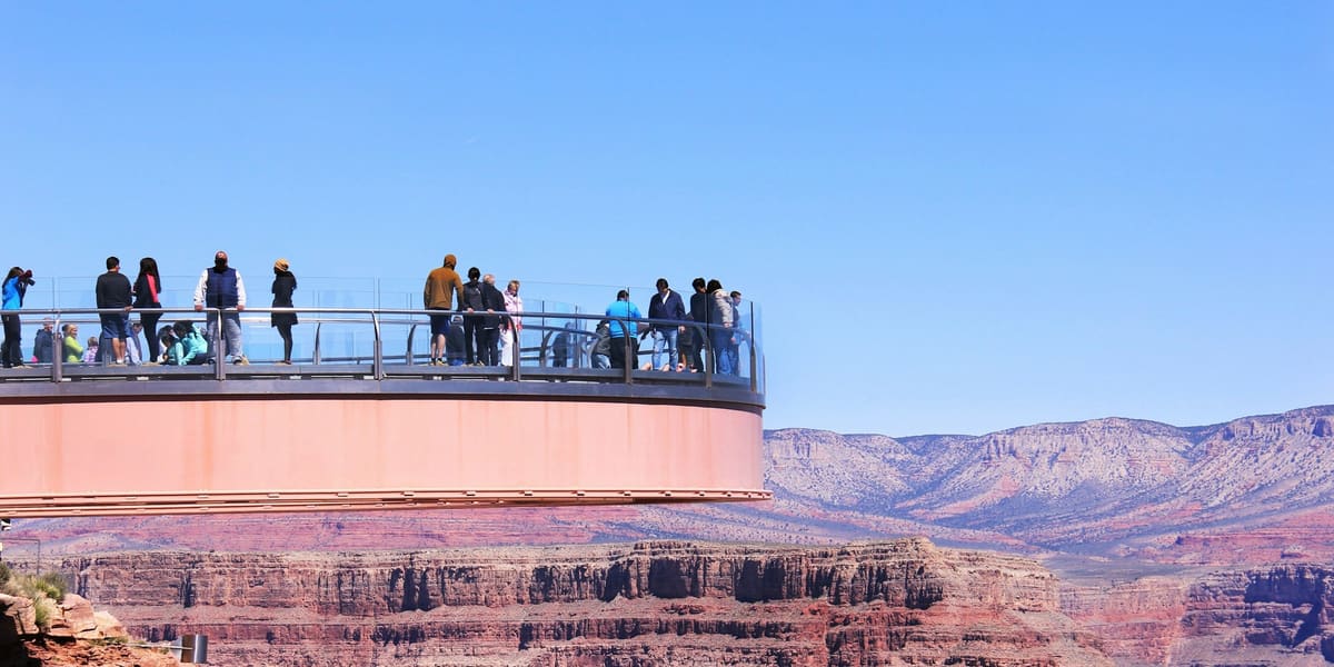 Visitors on the horseshoe-shaped glass Skywalk extending over the Grand Canyon West Rim under a clear blue sky