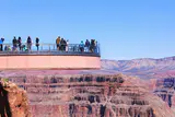 Visitors on the horseshoe-shaped glass Skywalk extending over the Grand Canyon West Rim under a clear blue sky