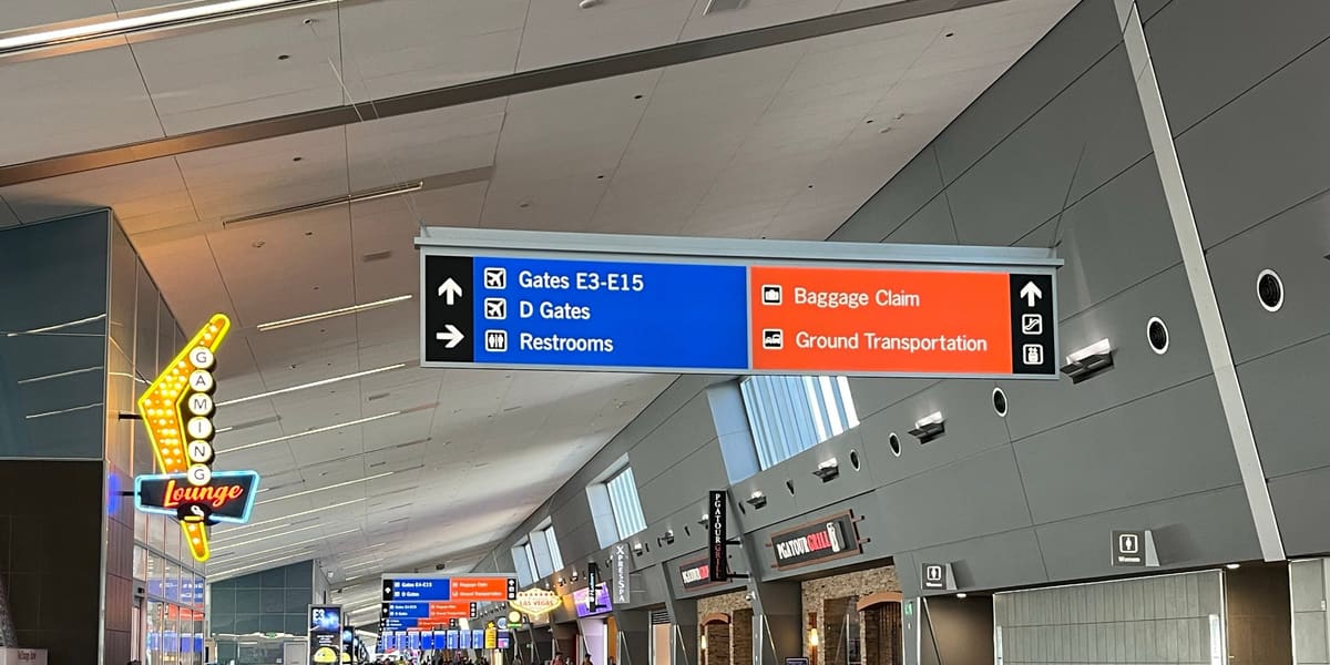Concourse at Harry Reid International Airport with overhead signs for gates, baggage claim and ground transportation