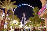 The High Roller observation wheel lit at night at the end of a palm-lined pedestrian promenade