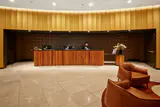 Hotel reception desk with wood panelling, a staff member at a computer and leather lobby armchairs