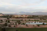 Red-roofed JW Marriott and Rampart Casino buildings beyond a golf course with mountains behind