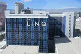 The LINQ hotel tower's blue-panelled facade and sign, seen from above with mountains in the distance
