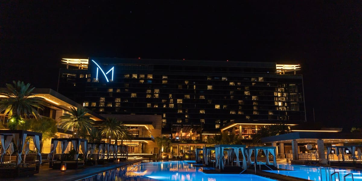 M Resort hotel tower lit at night behind a blue-lit pool lined with cabanas