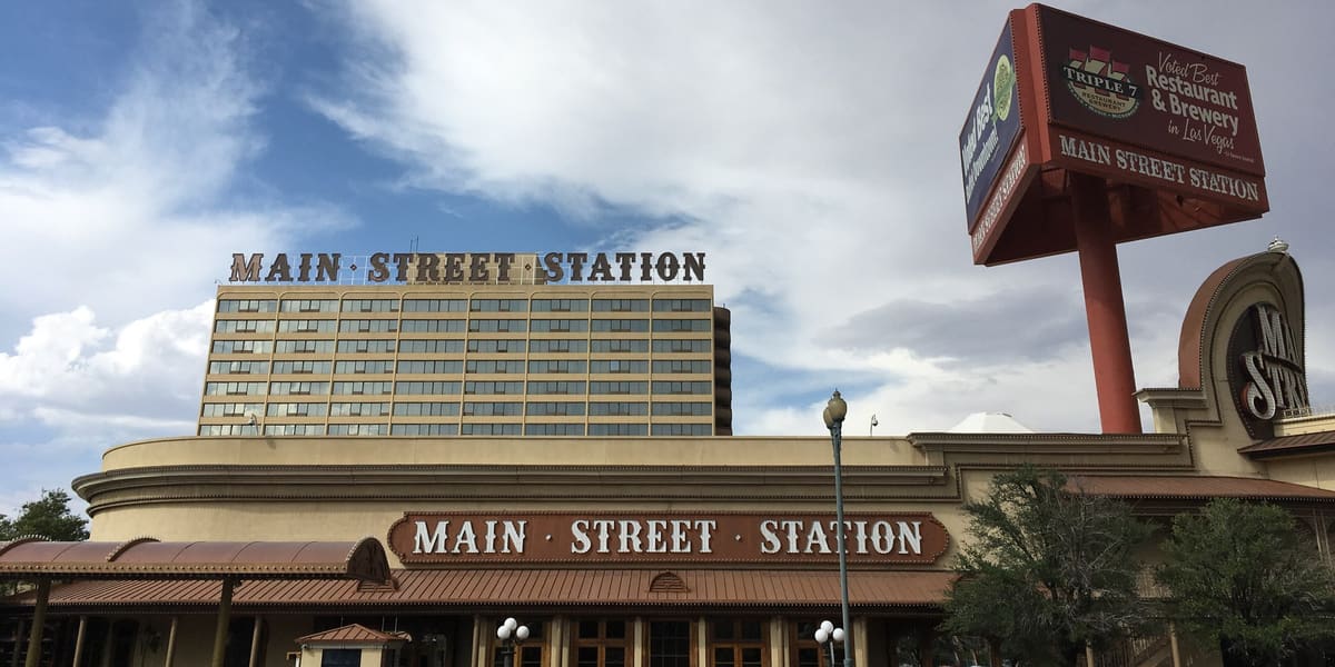Main Street Station hotel tower and casino frontage with its name in large letters under cloudy sky