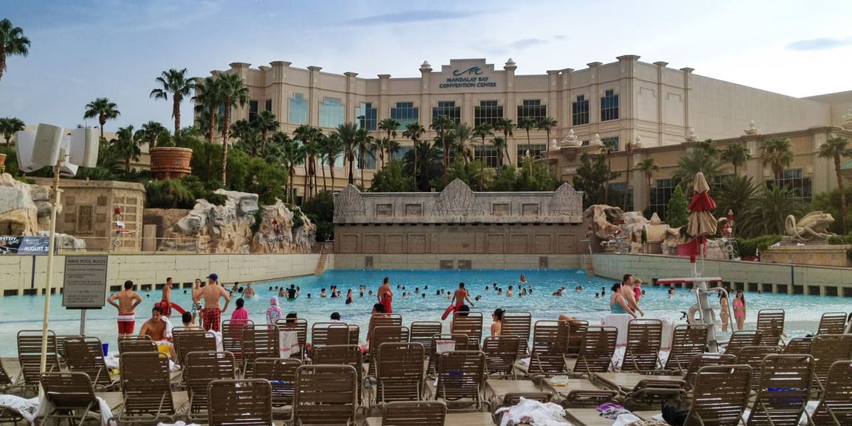 Rows of loungers in front of the sand-edged wave pool at Mandalay Bay Beach with palm trees beyond