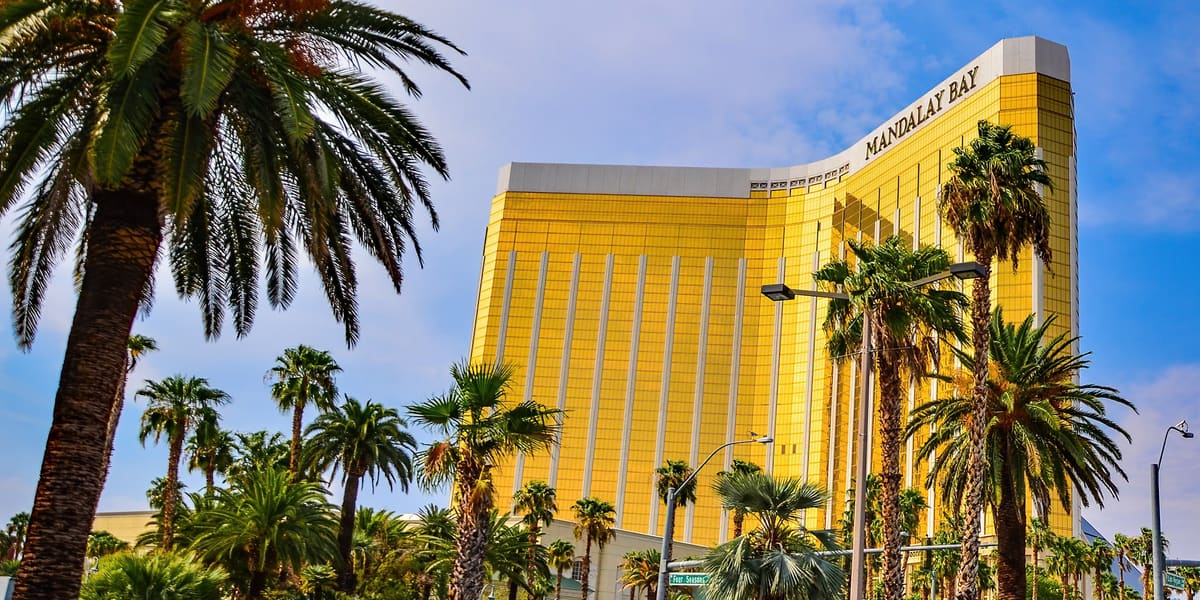 Gold-glass Mandalay Bay hotel tower rising above palm trees on a sunny day