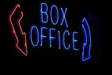 Blue neon Box Office sign with red and blue arrows glowing against a dark wall