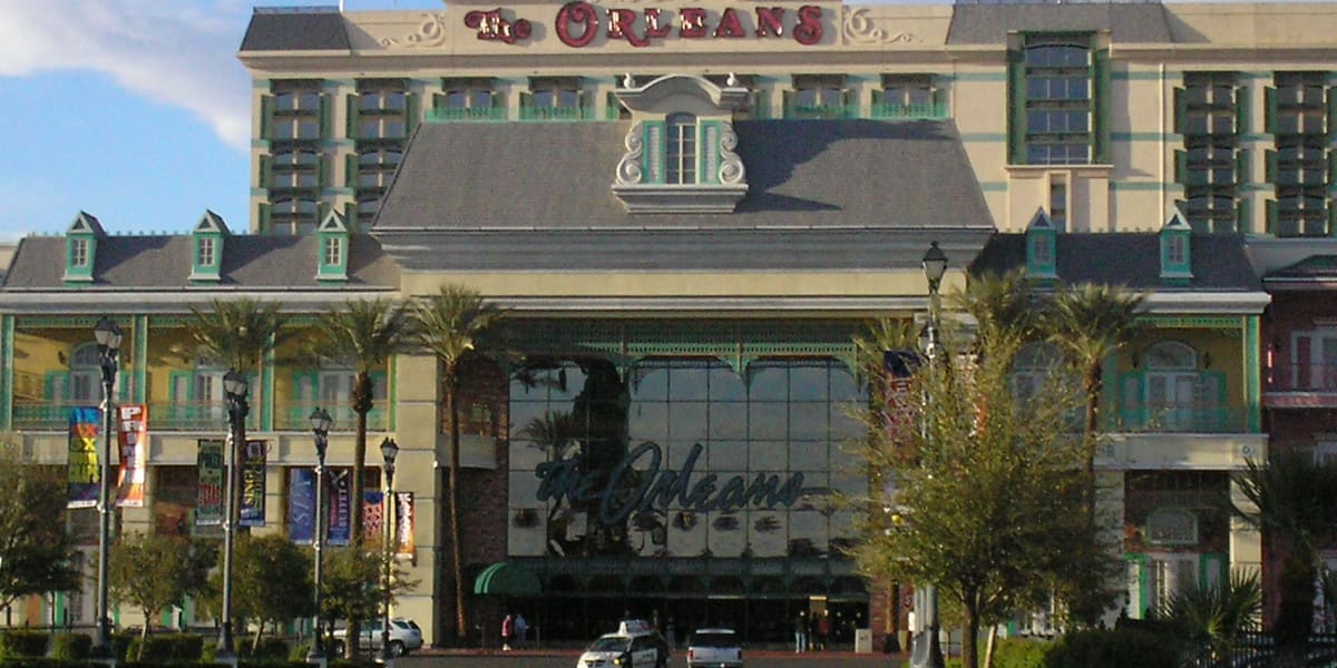 The Orleans hotel entrance and facade with its sign, palm trees and street in front