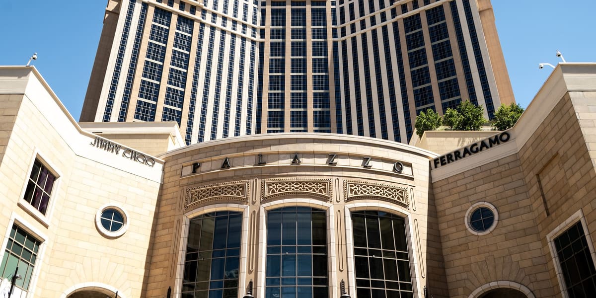 Stone entrance of The Palazzo with tall arched windows below the hotel's cream and glass tower