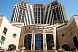 Stone entrance of The Palazzo with tall arched windows below the hotel's cream and glass tower