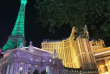 Paris Las Vegas at night, its Eiffel Tower replica lit green beside the illuminated hotel tower
