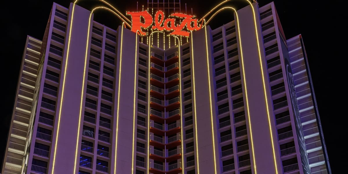 Plaza Hotel & Casino tower lit at night with red Plaza signs and gold arched lights