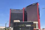 Red-framed dark glass hotel towers of Resorts World Las Vegas with Hilton and Conrad signage