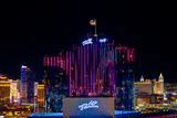 Rio hotel towers lit pink and blue at night with Rio signs and the Strip skyline behind