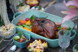 A roast turkey with vegetables in a serving dish surrounded by salads and side dishes on a festive table