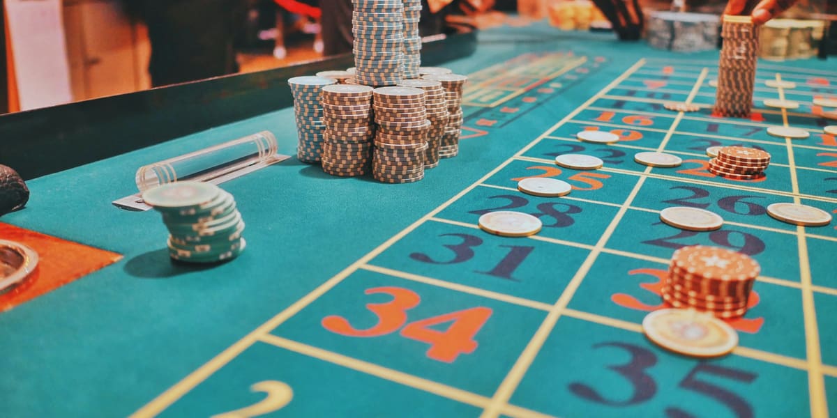 Stacks of casino chips on a green roulette table layout as players place bets