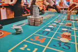 Stacks of casino chips on a green roulette table layout as players place bets