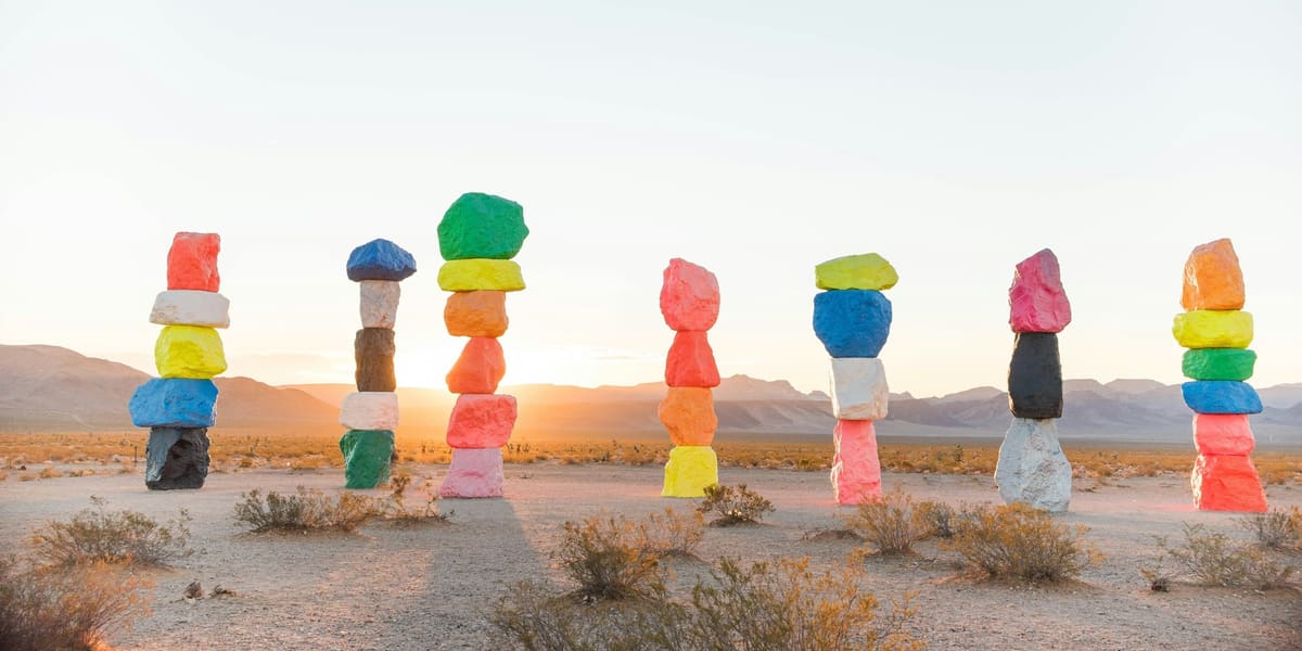 Brightly painted stacked boulder towers of Seven Magic Mountains in the desert at sunrise