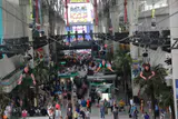 Zip line riders flying head-first above a crowded covered pedestrian mall beneath the SlotZilla tower