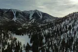 Snow-covered mountain slopes and pine forest under a cloudy sky on Mount Charleston