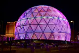 The Sphere in Las Vegas at night, its LED exosphere lit with a purple and pink geometric pattern