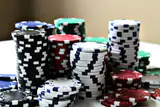 Tall stacks of black, red, blue, white and green poker chips on a table
