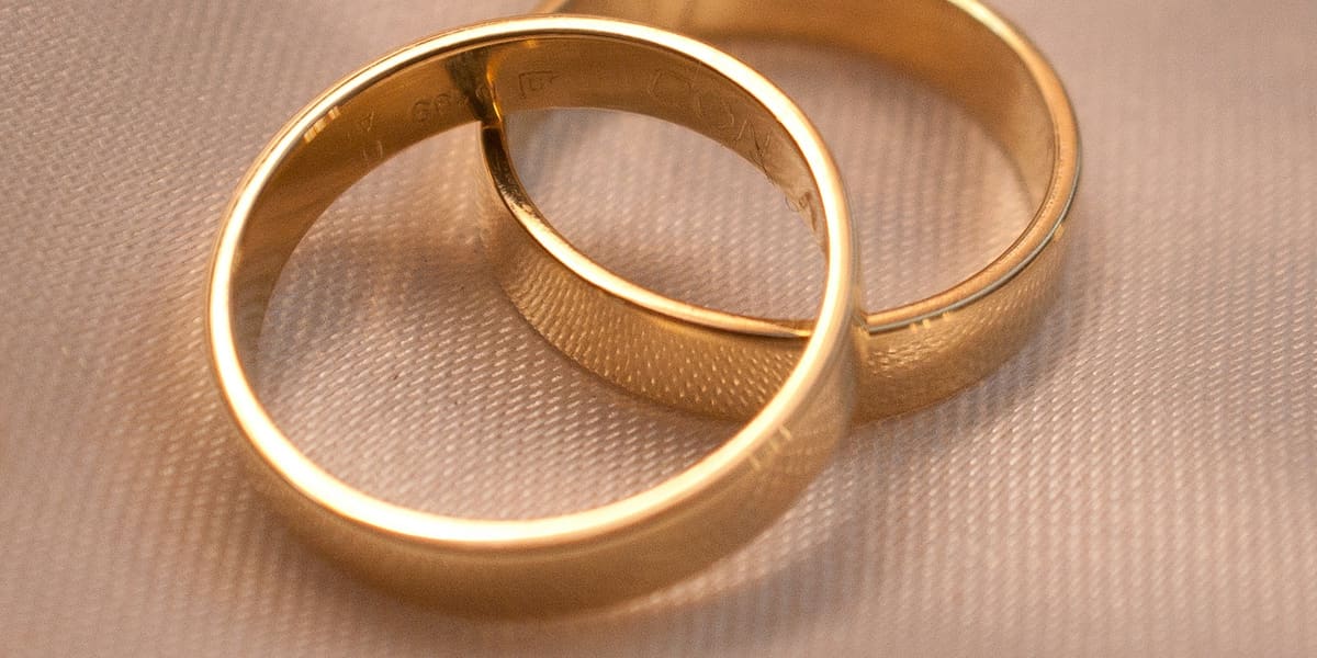 Two interlocking gold wedding bands resting on cream textured fabric