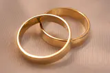 Two interlocking gold wedding bands resting on cream textured fabric