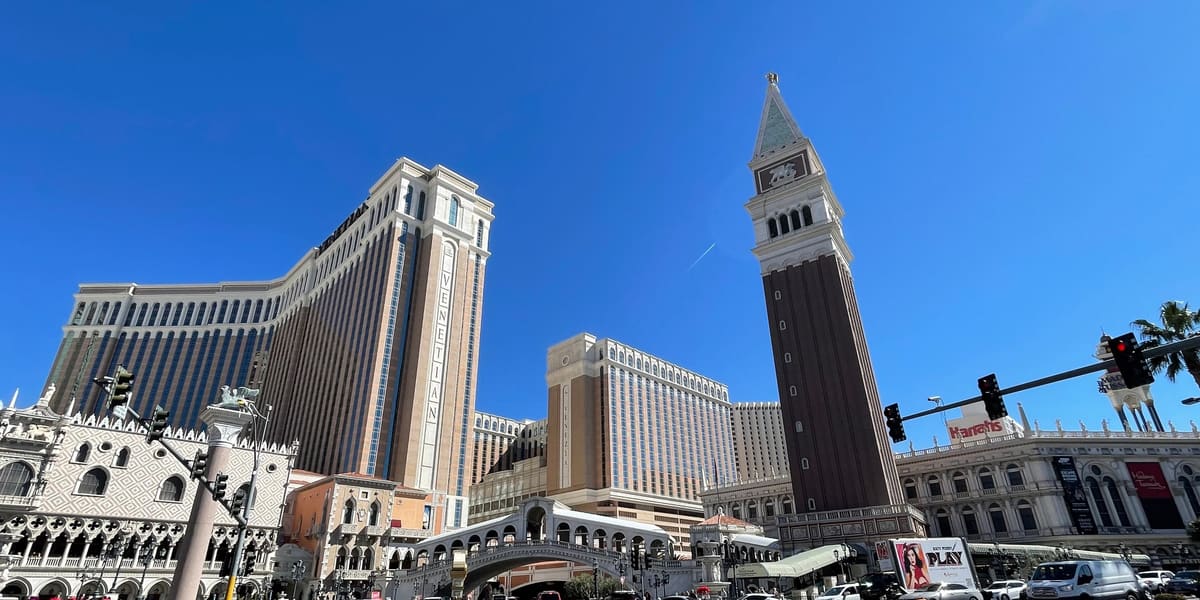 The Venetian's bell tower, Rialto-style bridge and hotel towers seen across Las Vegas Boulevard on a sunny day