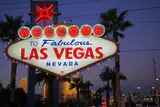 The Welcome to Fabulous Las Vegas sign lit up at dusk, framed by palm trees