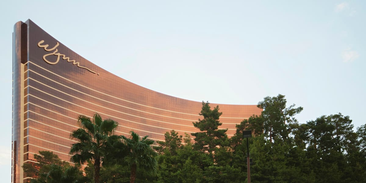 The curved bronze-glass Wynn hotel tower rising above a line of green trees